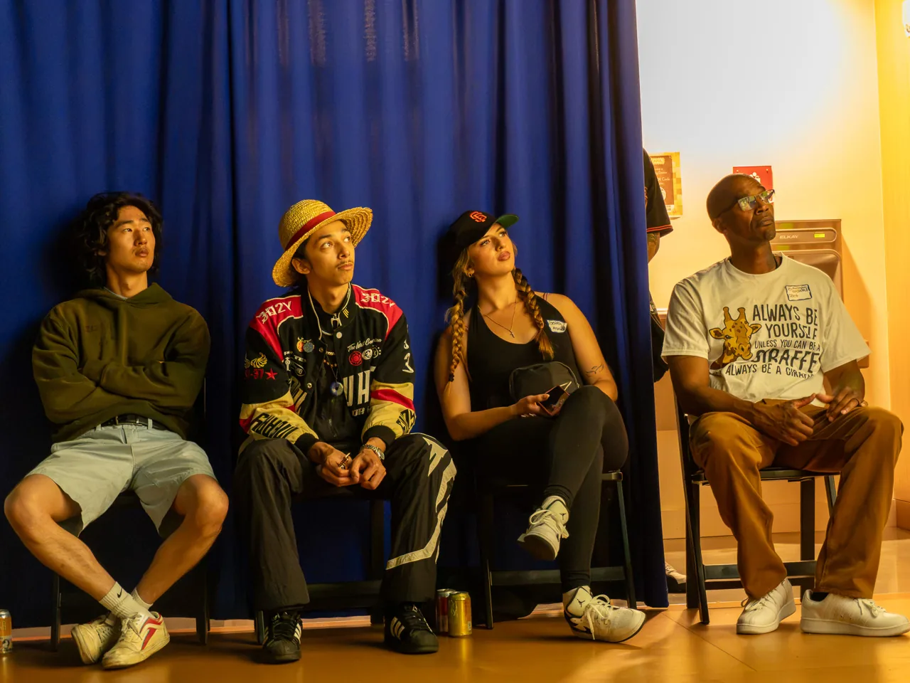 Four guests sit together against the blue curtain during the screening.