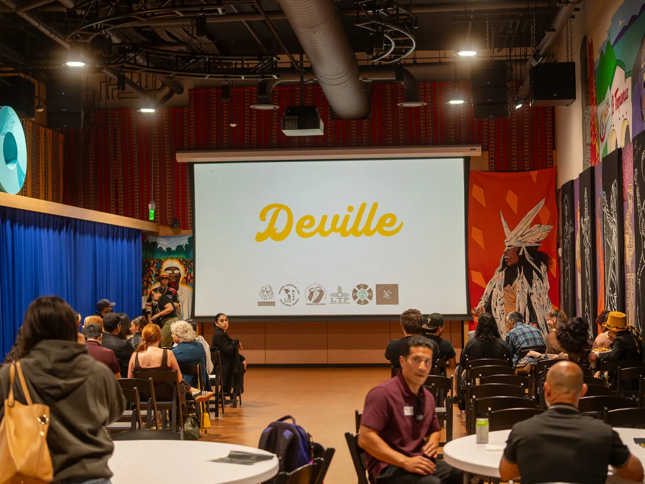Guests settle into the screening room while the Deville title is projected at the front.