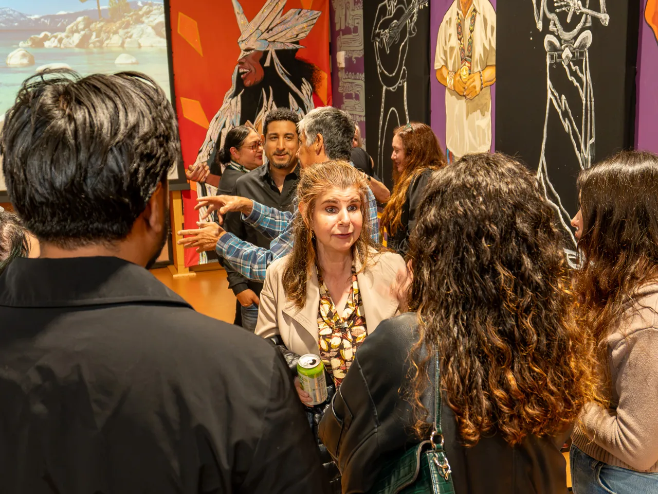 Guests chat in the mural-lined room after the screening.