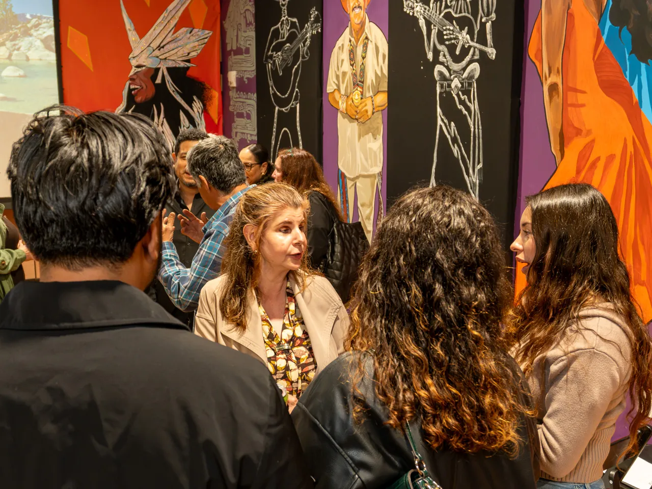Guests chat in the mural-lined room after the screening.