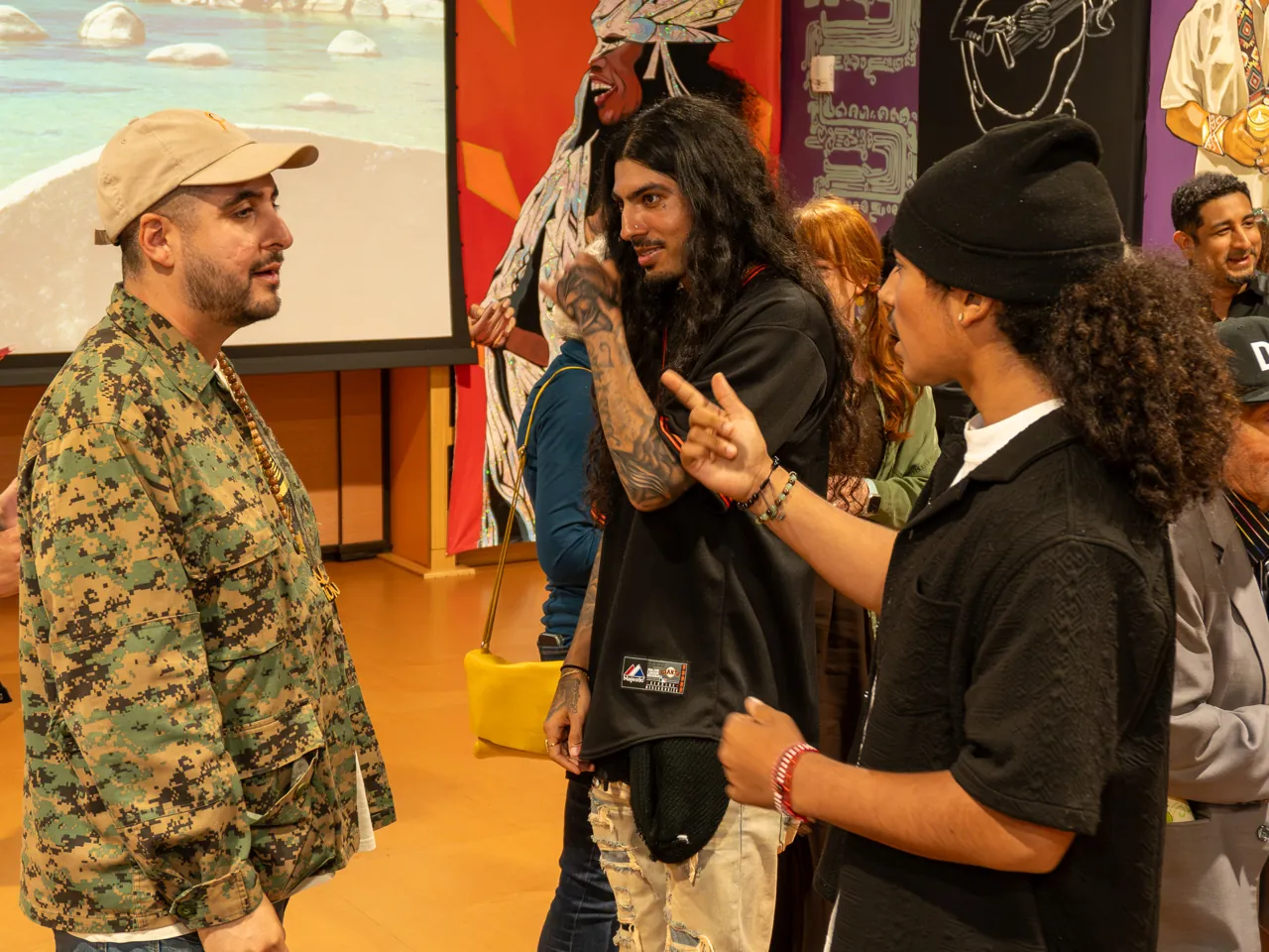 Three guests converse, including a long-haired person and a person in a patterned jacket.
