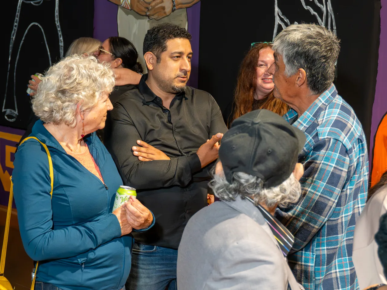 A small circle of guests talks in front of a mural.