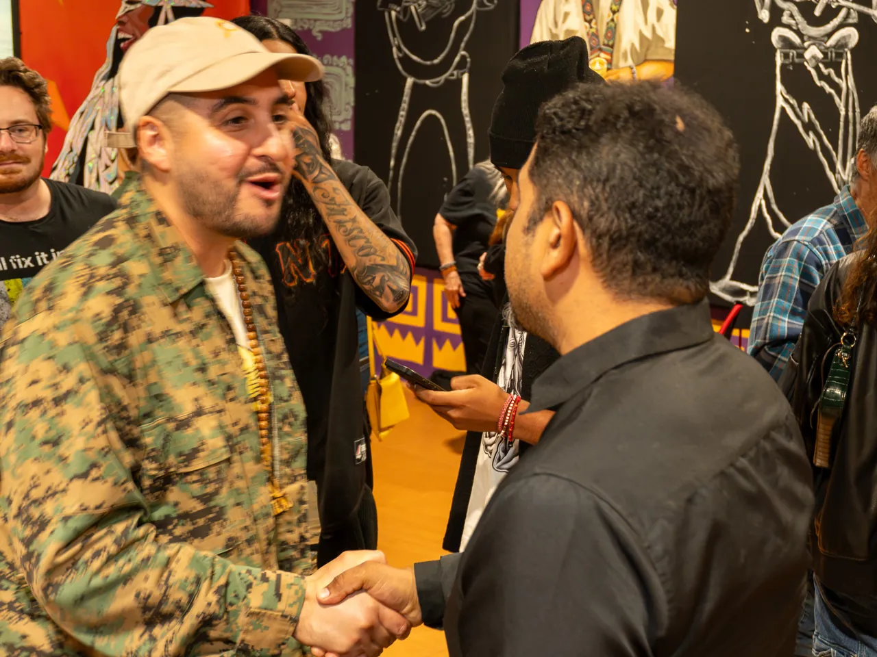 Two guests talk face to face near a mural.