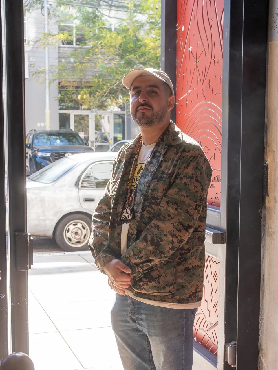 A guest in a cap and patterned jacket stands in the entrance doorway.
