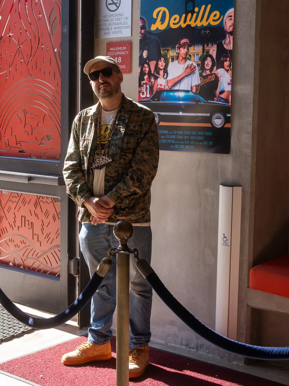 A guest poses beside the Deville poster near the entrance.