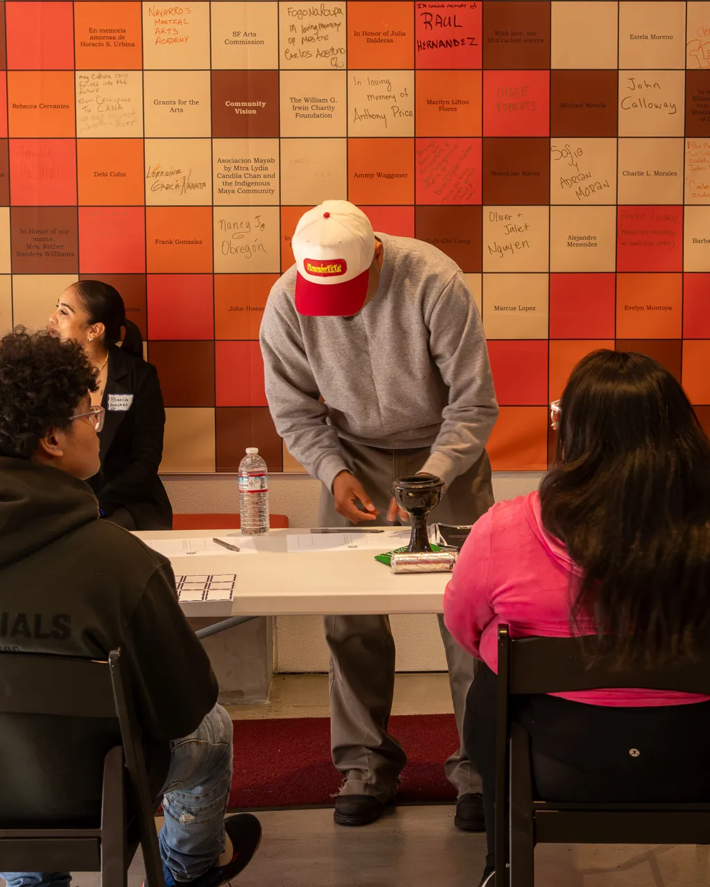 A guest leans over the welcome table while other guests sit nearby.
