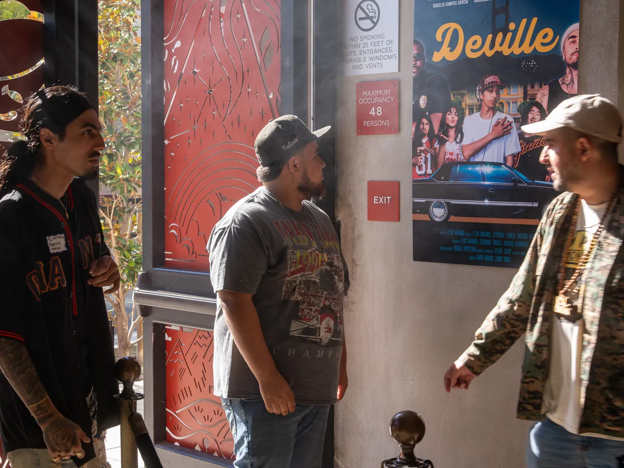 Guests greet one another in front of the Deville poster.
