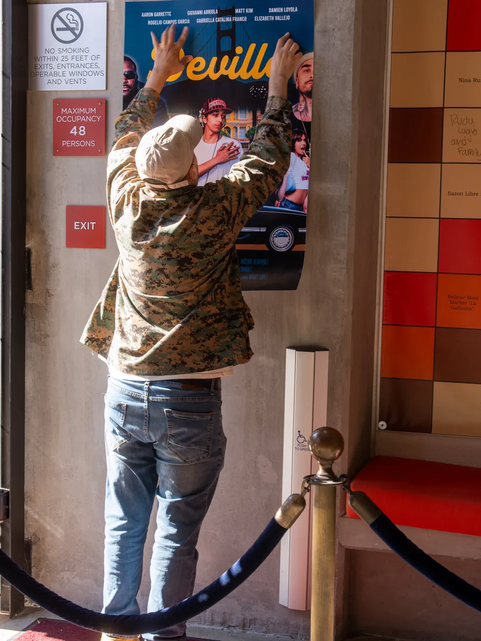 A guest stands beside a Deville poster near the entrance.