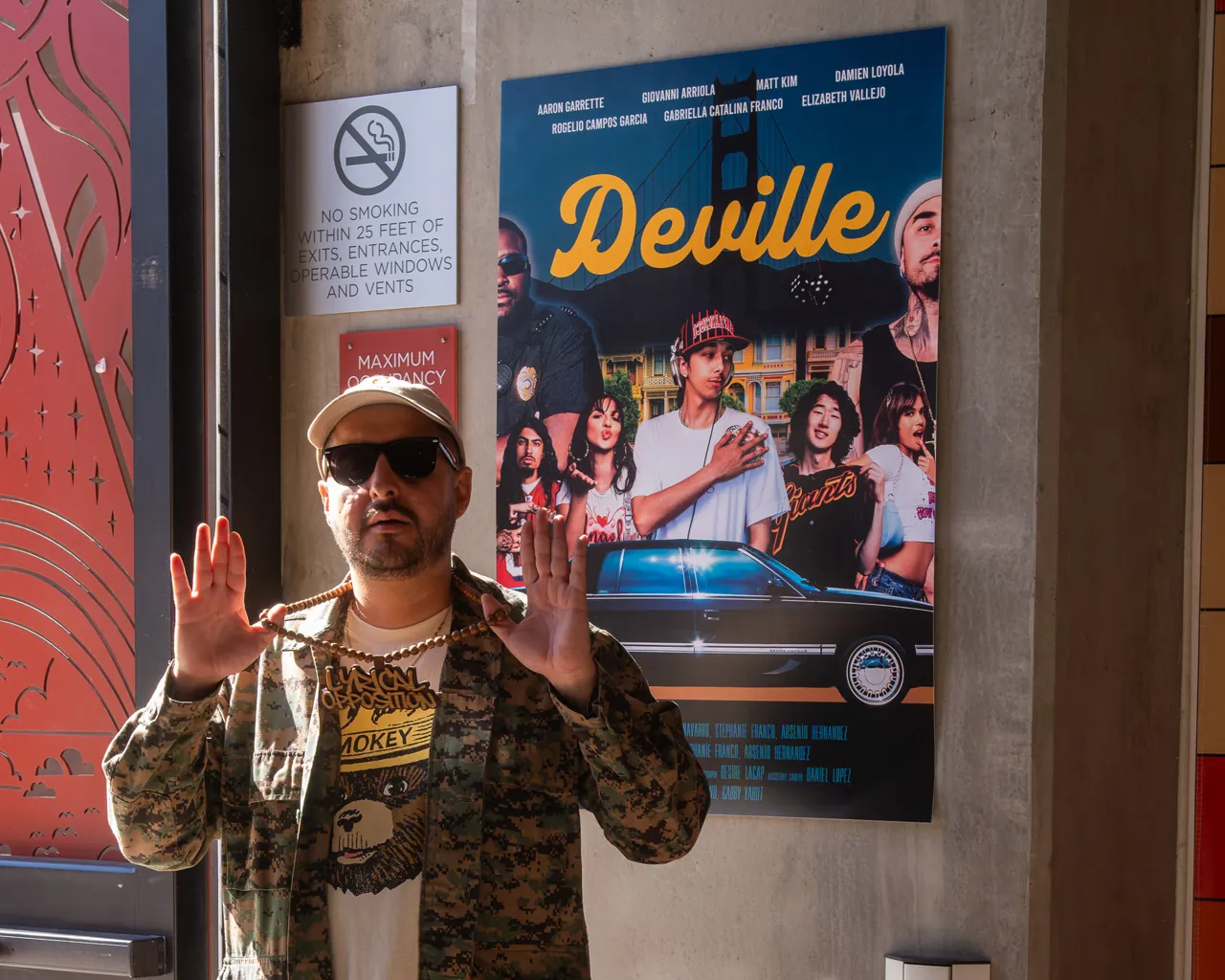 A guest poses beside the Deville poster near the entrance.