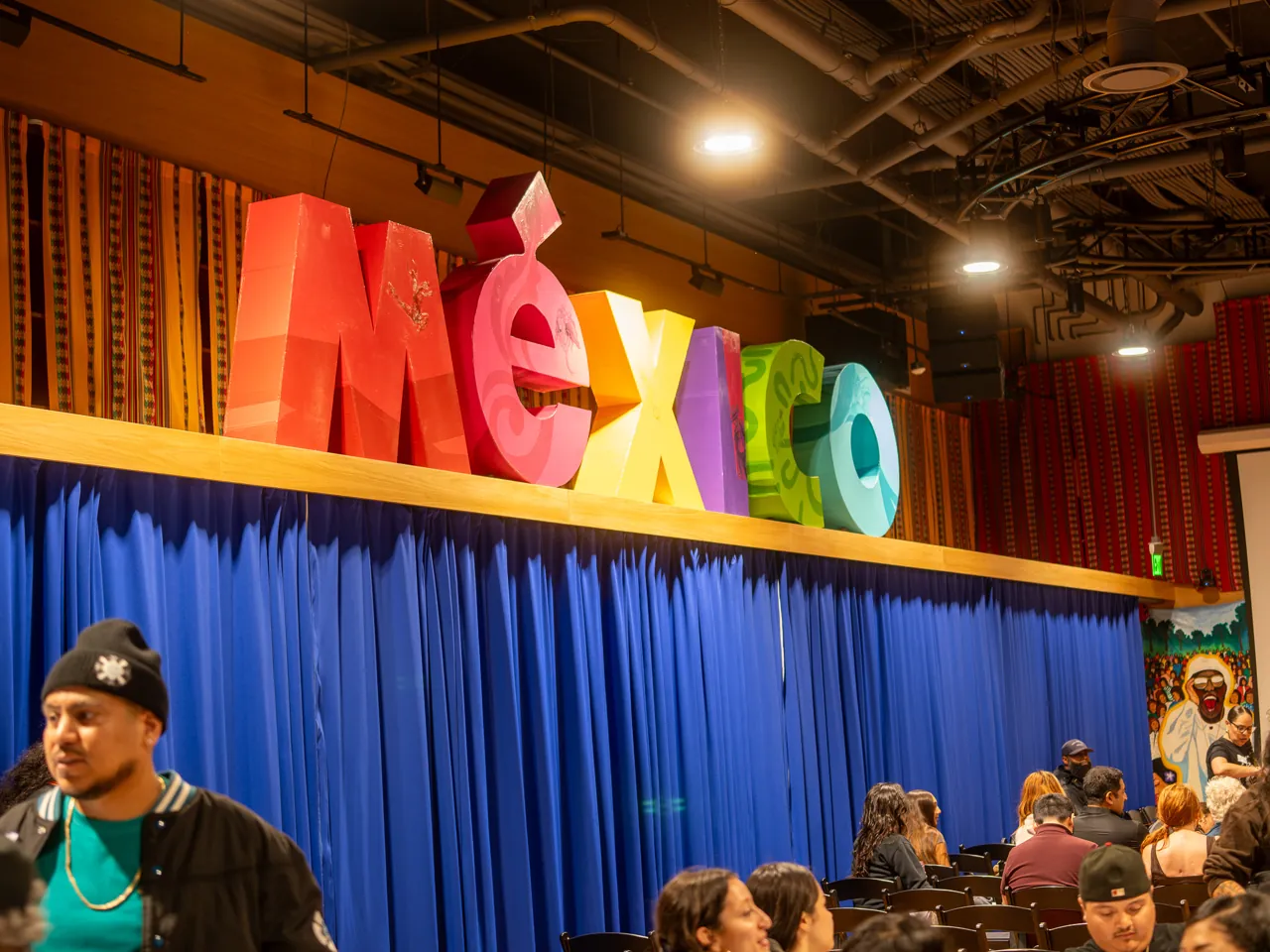 Colorful MEXICO letters hang above the blue curtain in the event room.