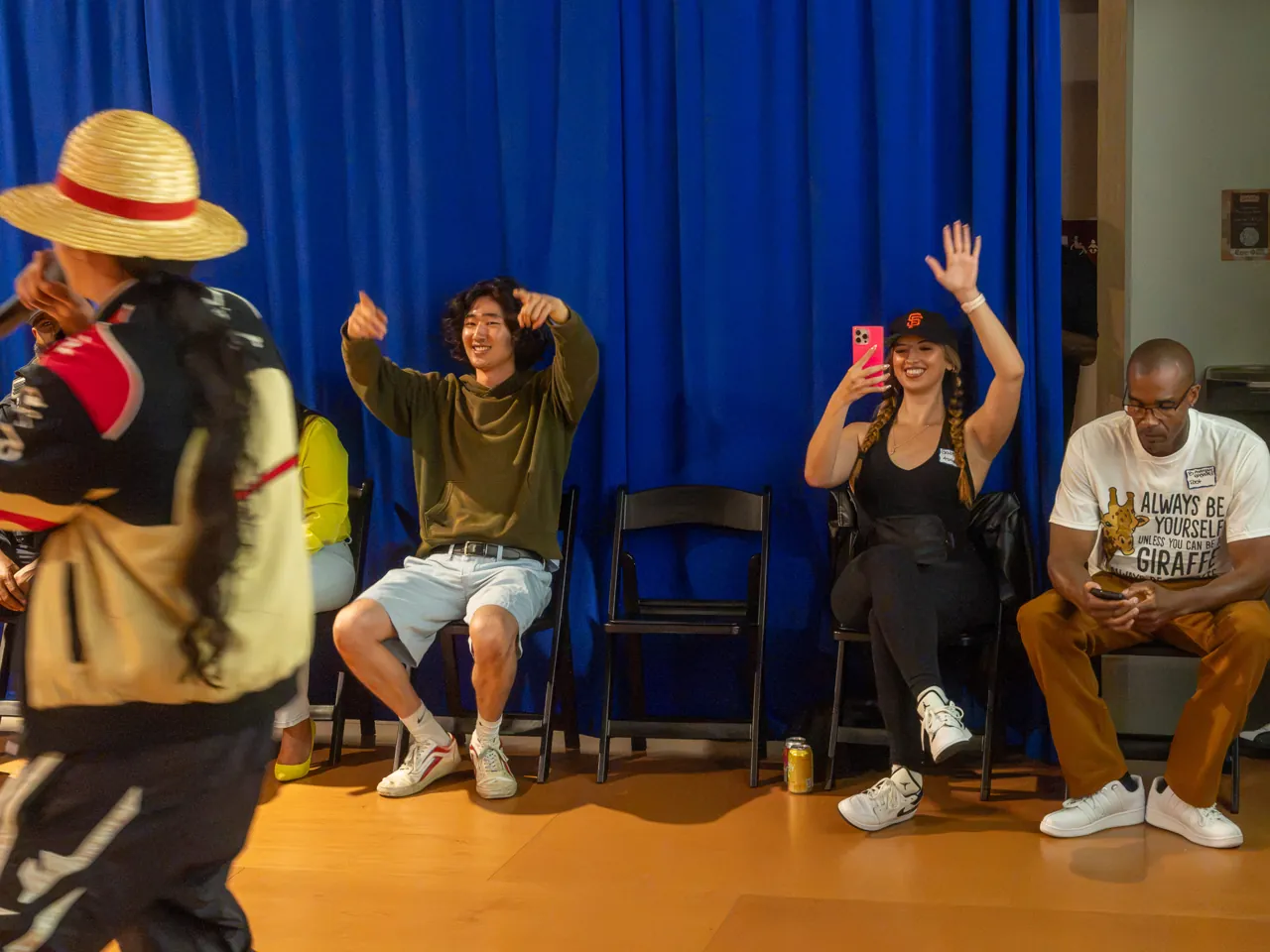 Seated guests raise their hands behind a performer in a straw hat.