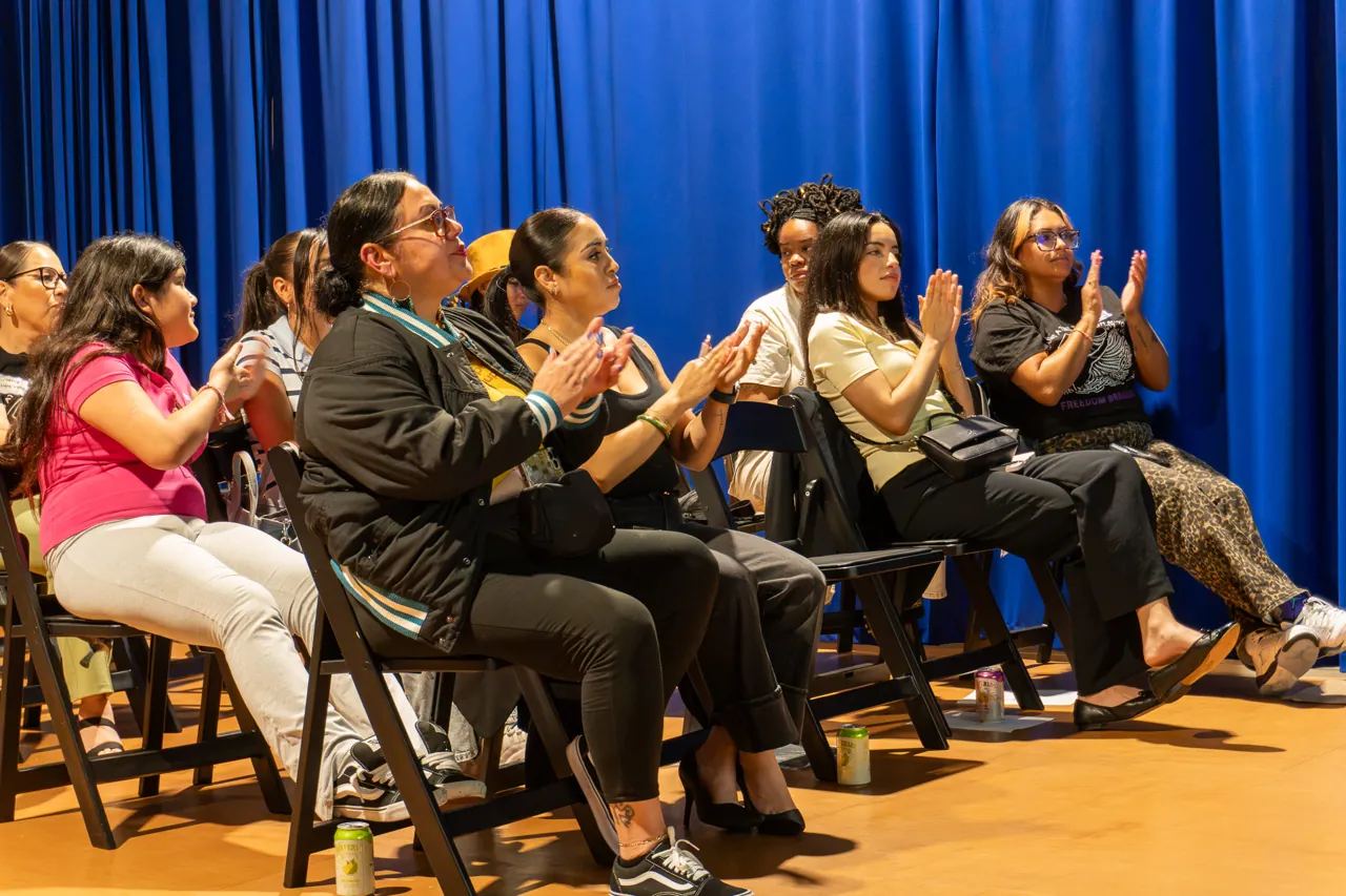 Guests seated against the blue curtain listen during the discussion.