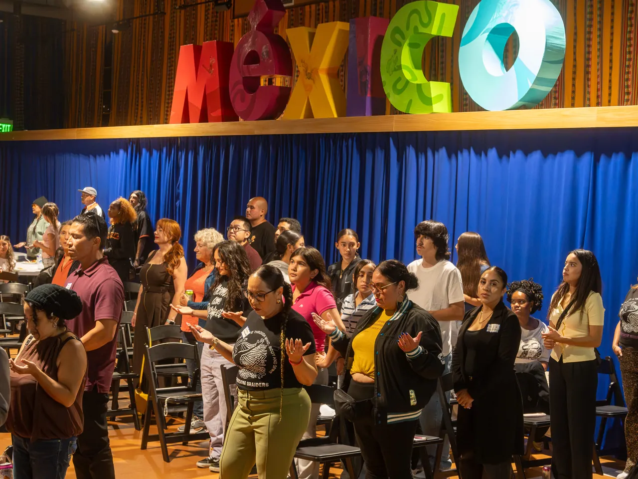 Guests stand together between rows of chairs during the community gathering.