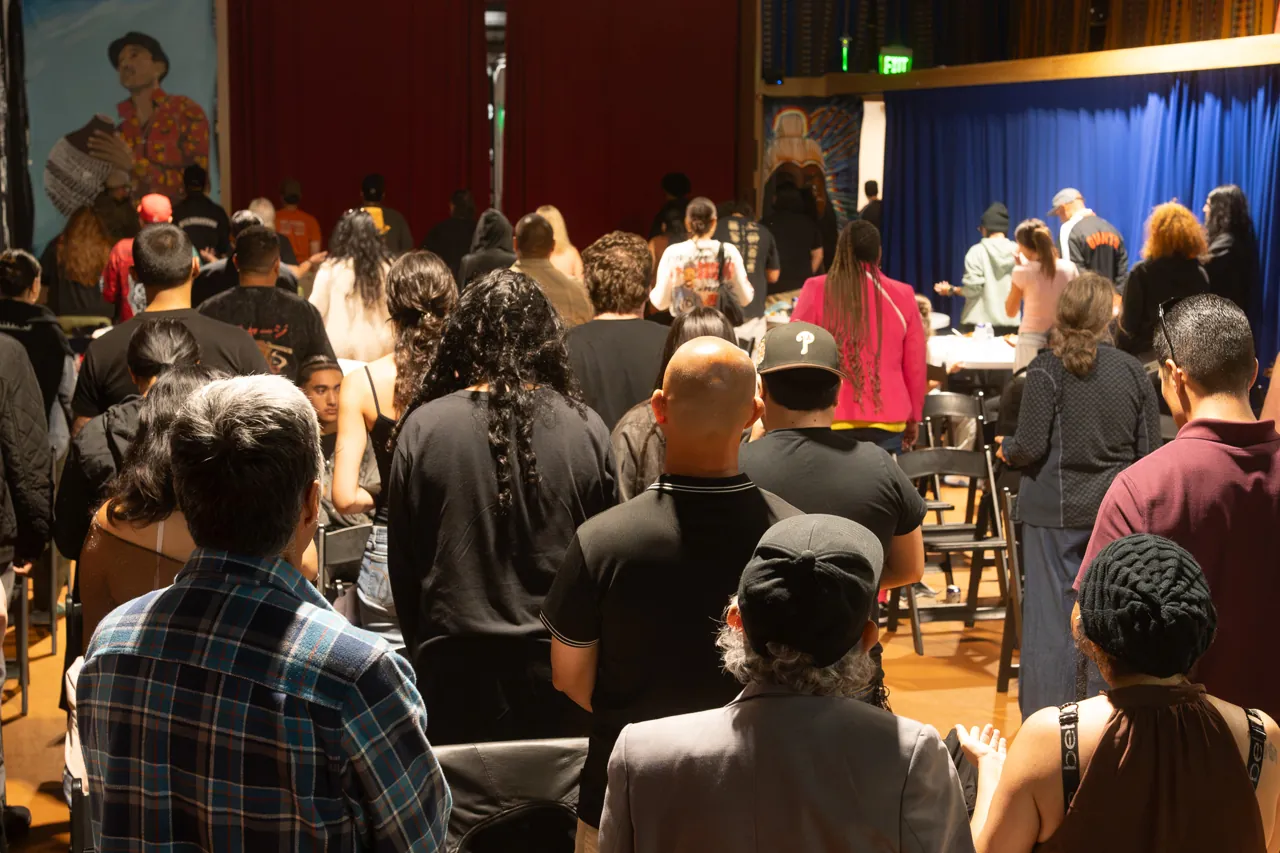 Guests stand together between rows of chairs during the community gathering.