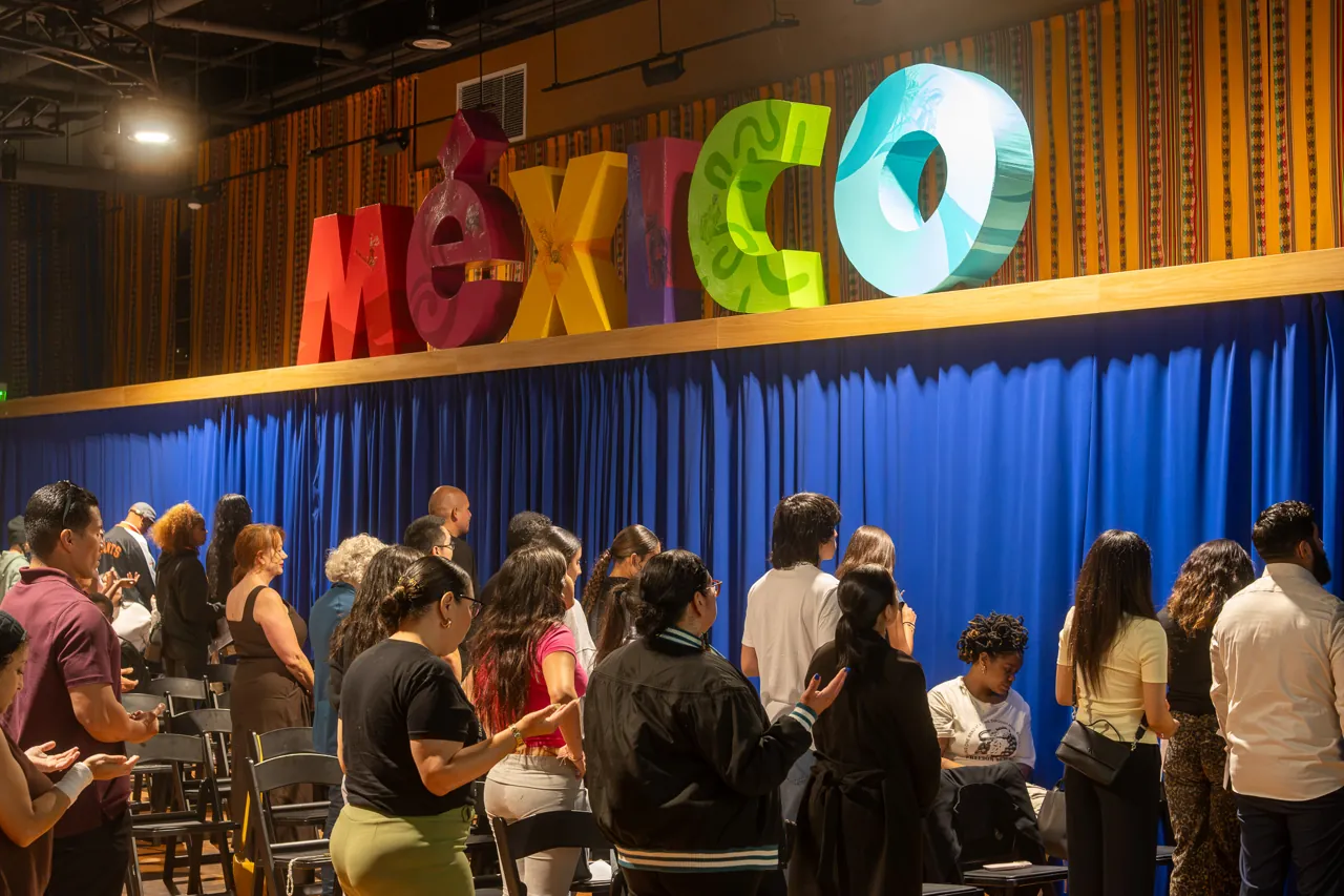 Guests stand together between rows of chairs during the community gathering.