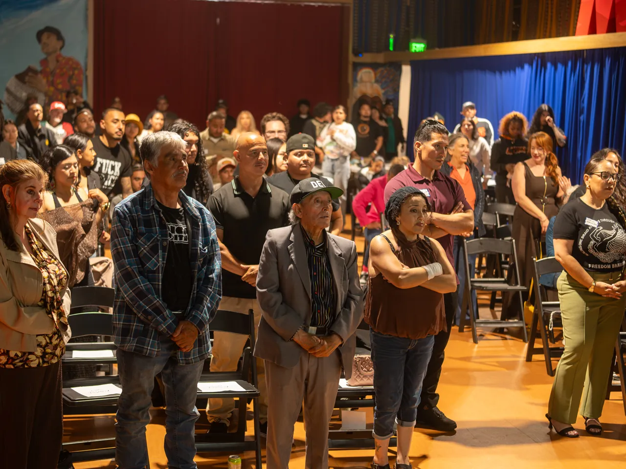Guests stand together between rows of chairs during the community gathering.