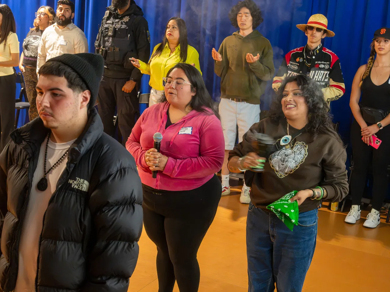A closer view of standing guests, including a person in pink and a person holding green fabric.