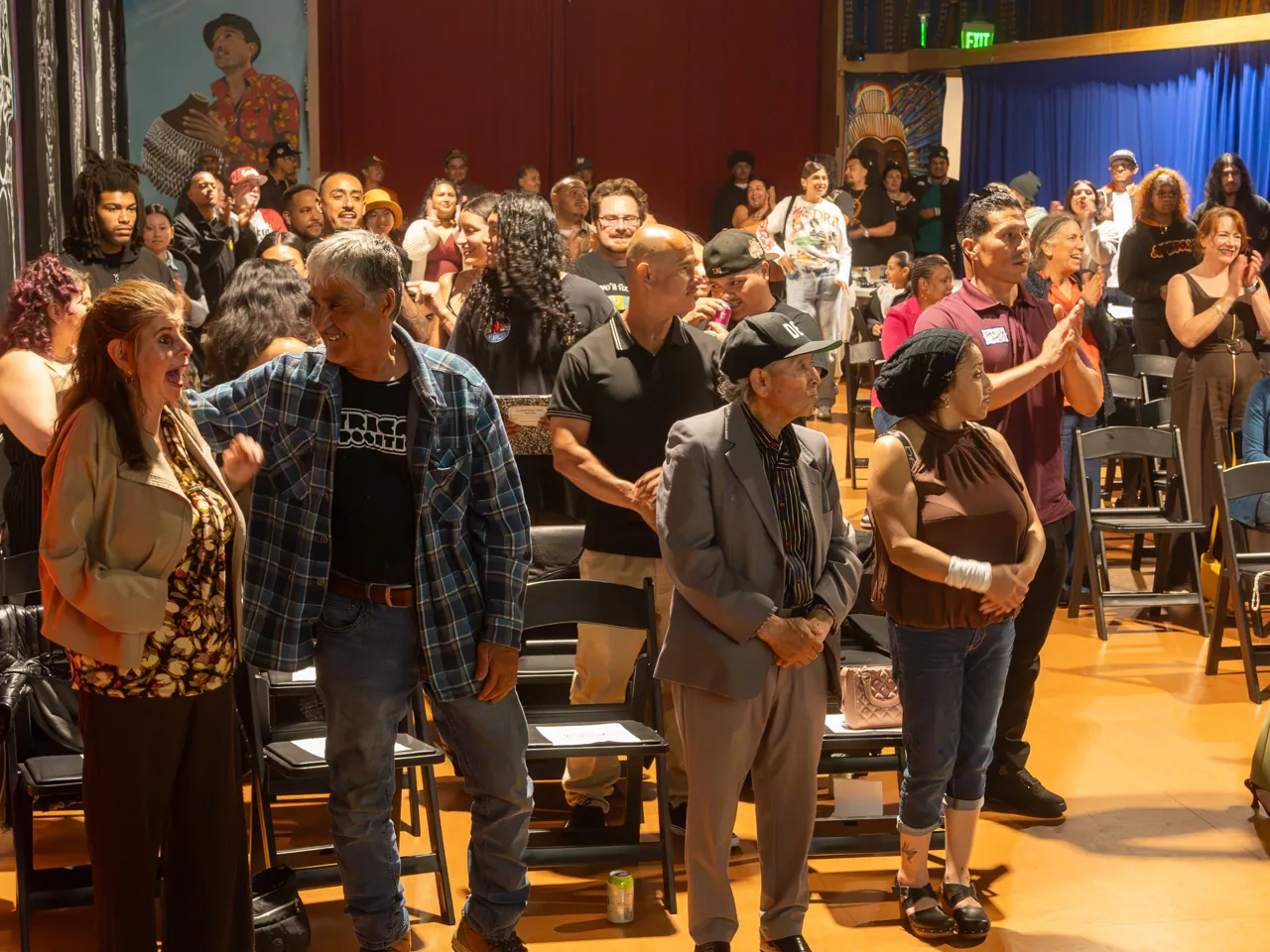 Guests stand together between rows of chairs during the community gathering.