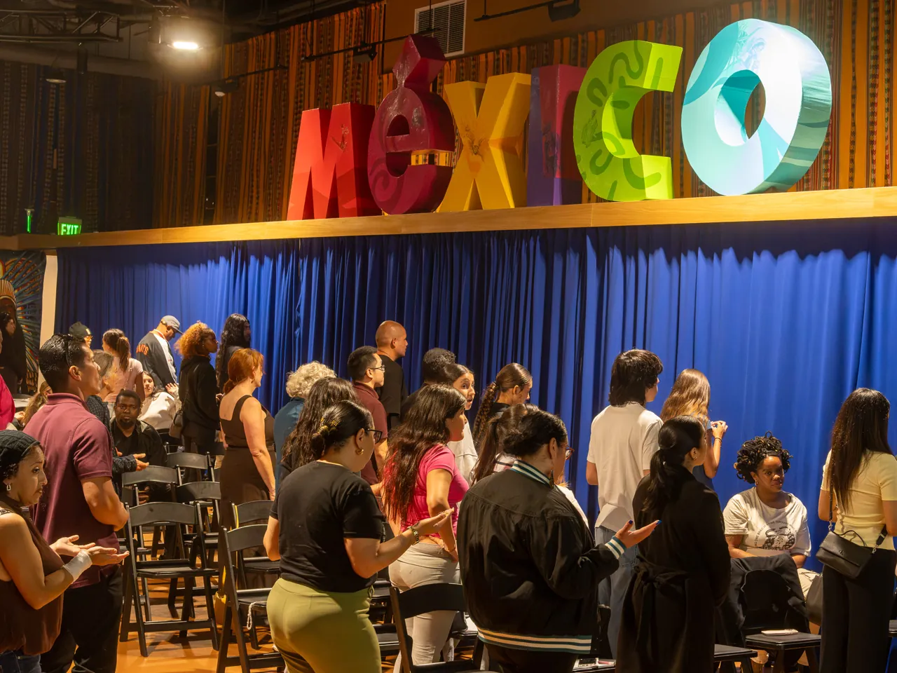 Guests stand together between rows of chairs during the community gathering.