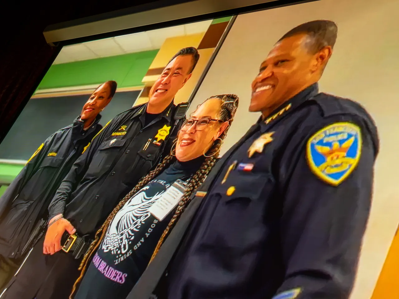 The projection screen shows four uniformed officers standing together.