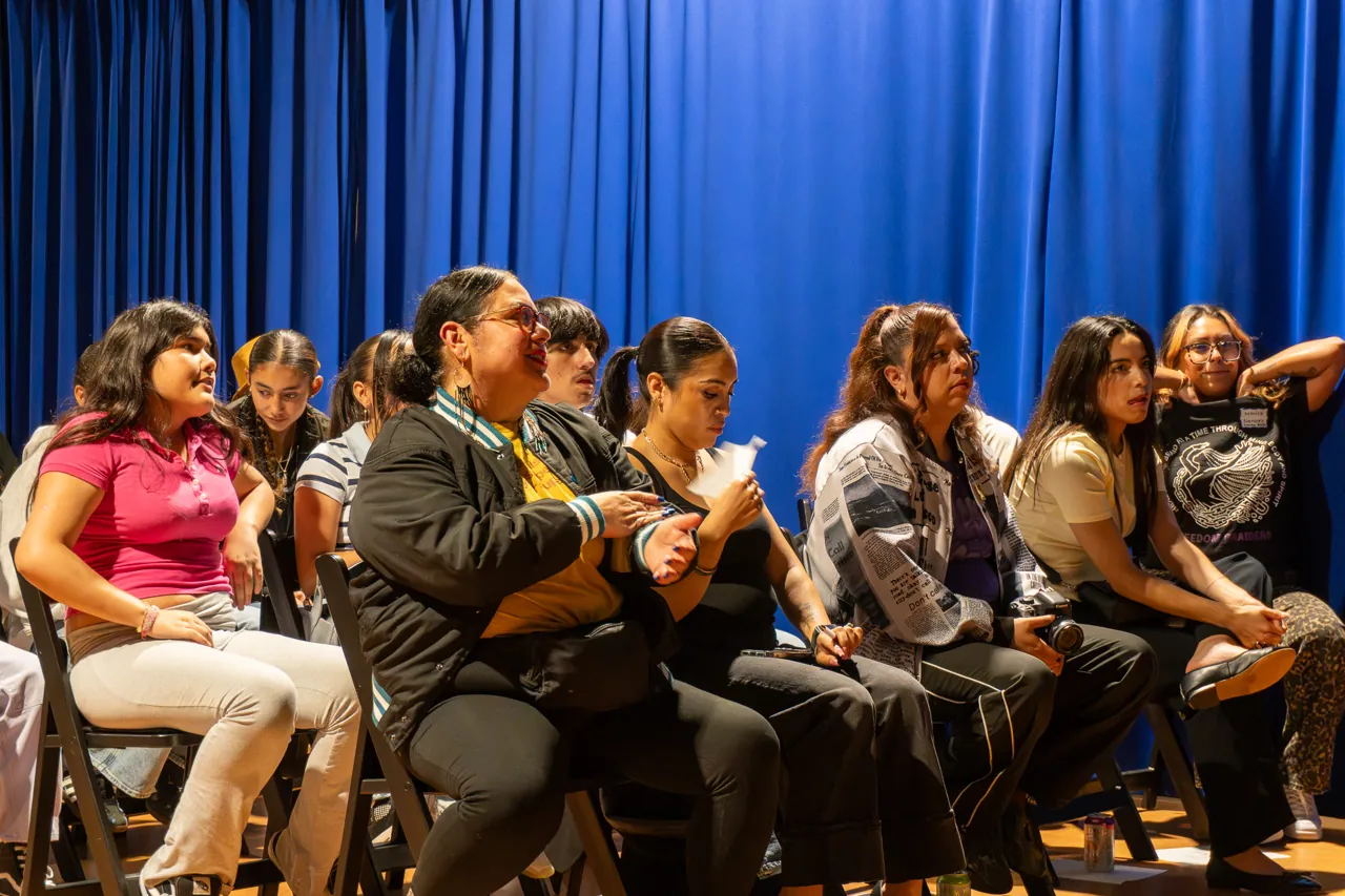 Guests seated against the blue curtain listen during the discussion.