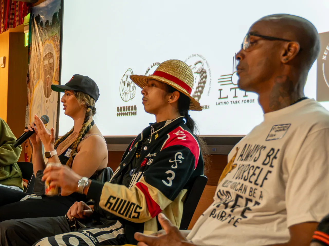 Panel participants listen as a person in a black cap speaks at the end of the row.