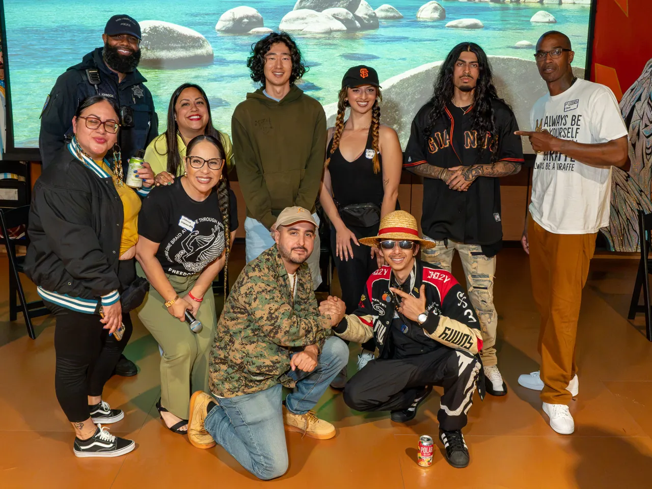 A group poses in front of the projection screen, with several guests crouching in the front row.