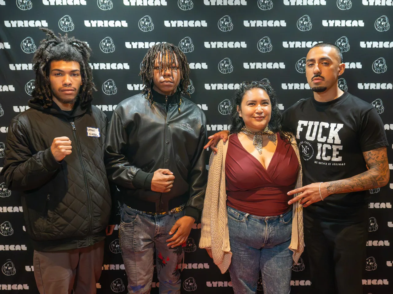 Four guests pose in front of the black event photo backdrop.