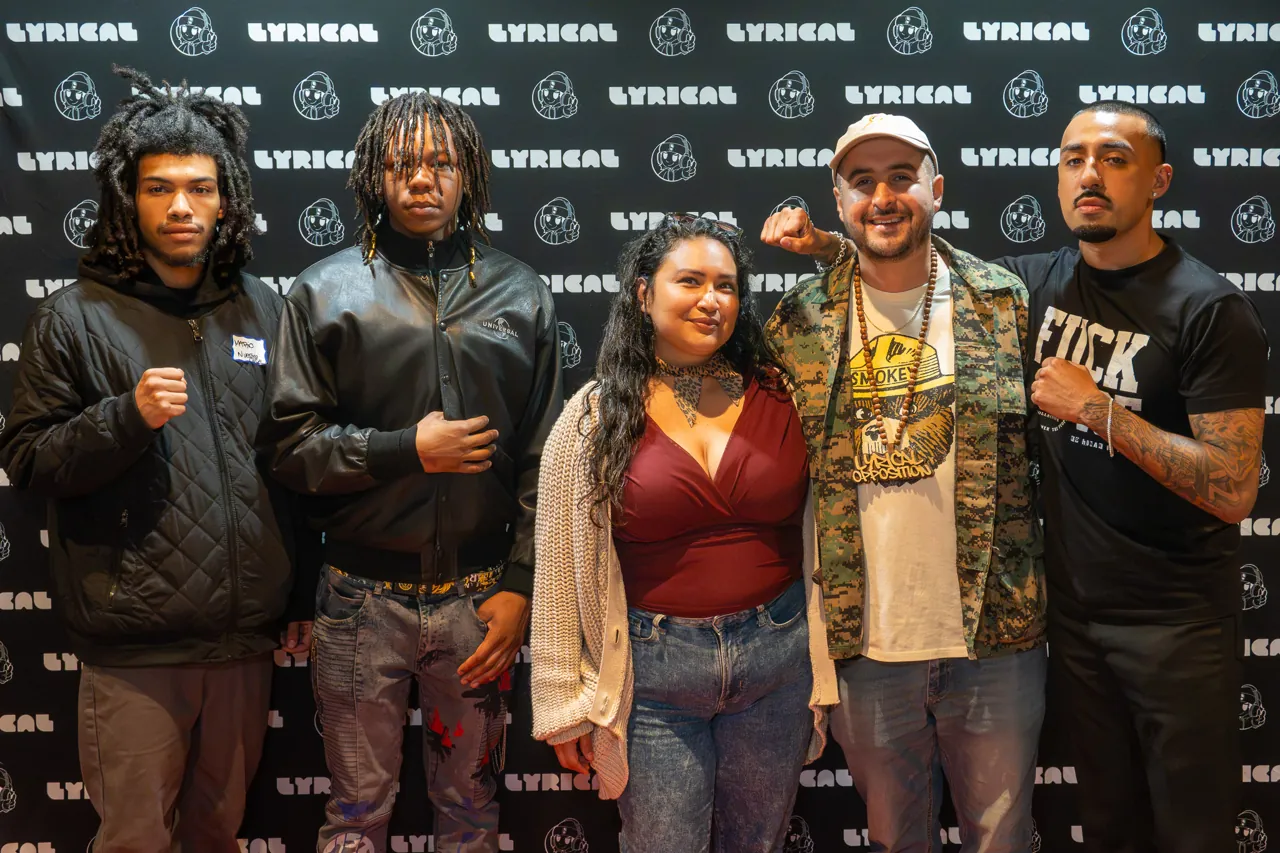 Five guests pose in front of the black event photo backdrop.