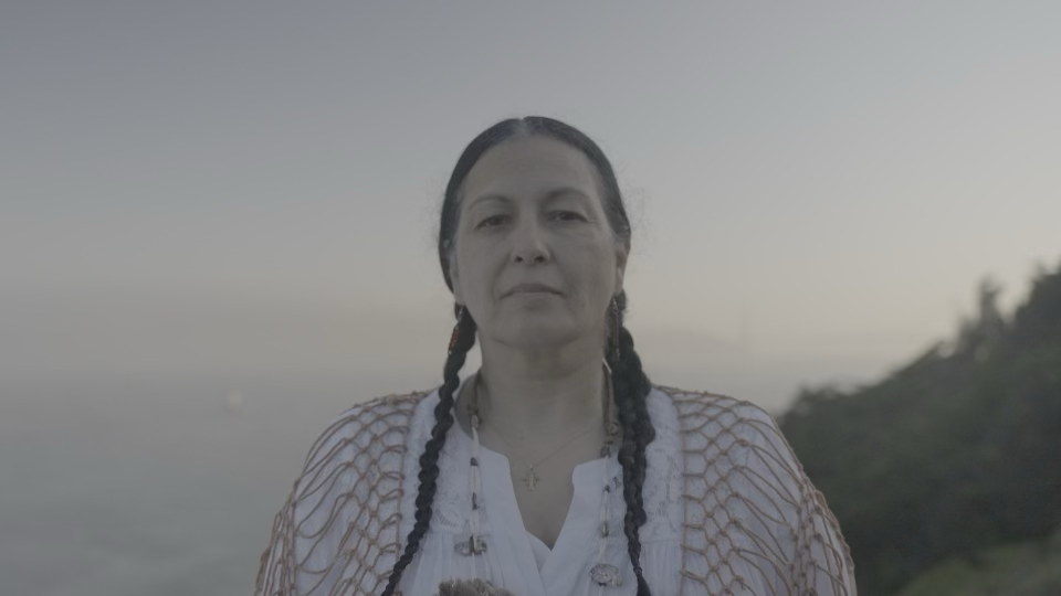 A person with two braids standing outdoors.