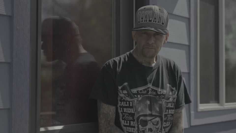 A person in a cap standing beside a window.