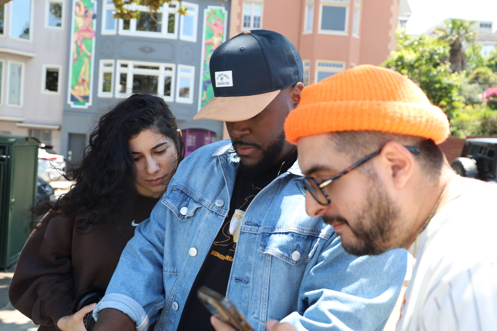 Three crew members looking at a phone on a San Francisco street.