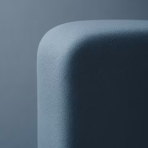 Close-up view of a rounded corner of a textured, dark gray-blue rectangular object against a matching background.