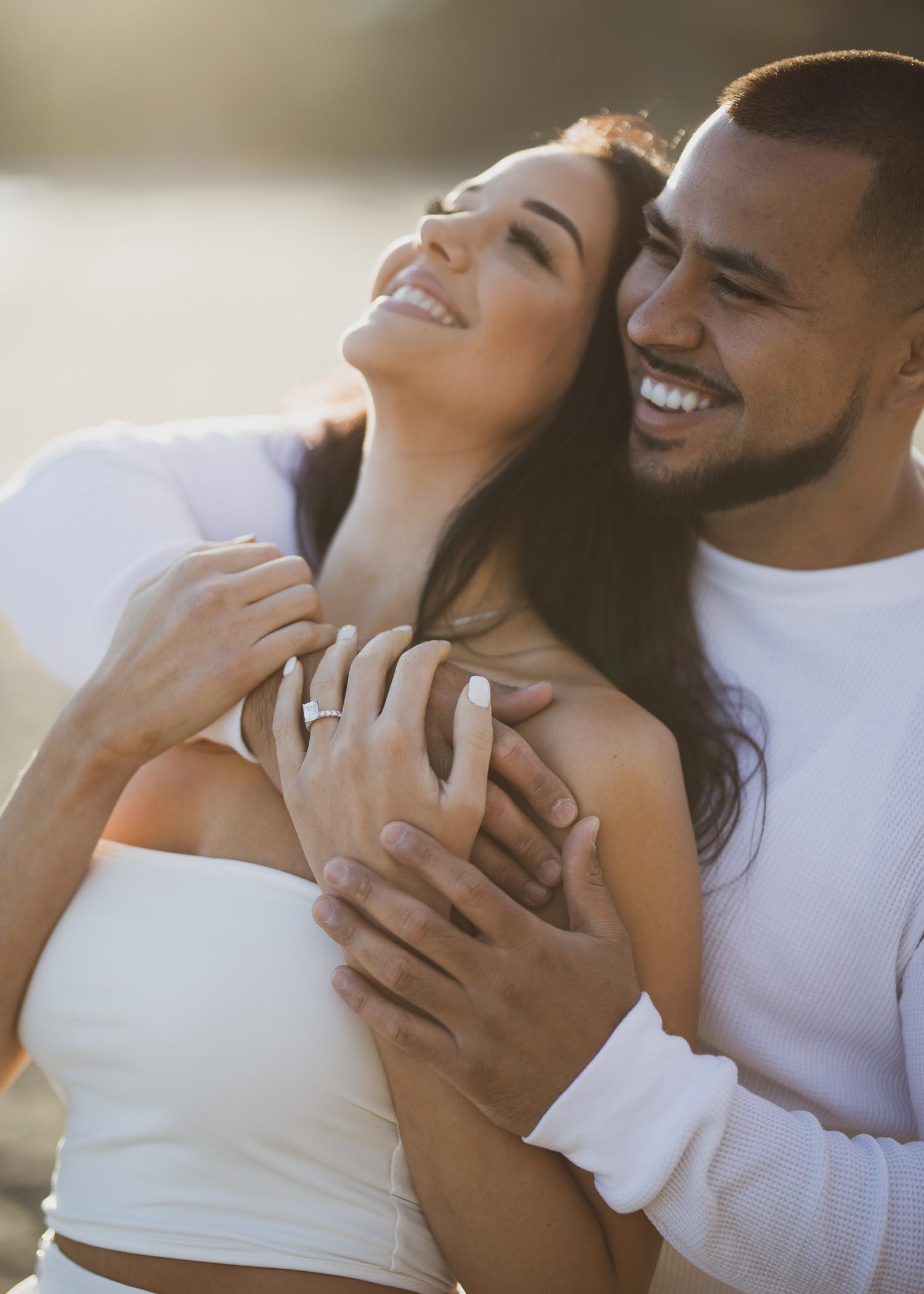 engaged couple laughing and embracing on the ocean