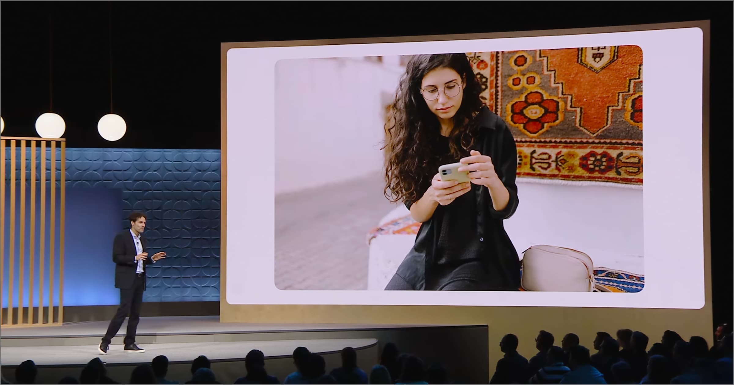 A still from the Google Marketing LIve Keynote where Google AI Tools for Ads were announced, with a man on a stage and a photo of a woman on her phone