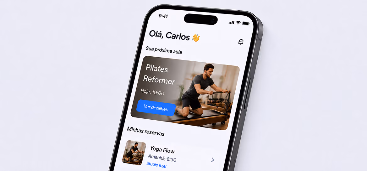 Smartphone showing fitness app greeting ‘Hello, Carlos’ with upcoming Pilates Reformer class at 10 AM and Yoga Flow booking.