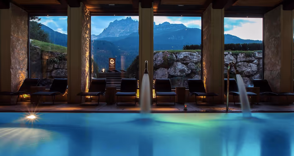 Indoor heated pool at Rosapetra Spa Resort in Cortina d’Ampezzo with mountain backdrop.