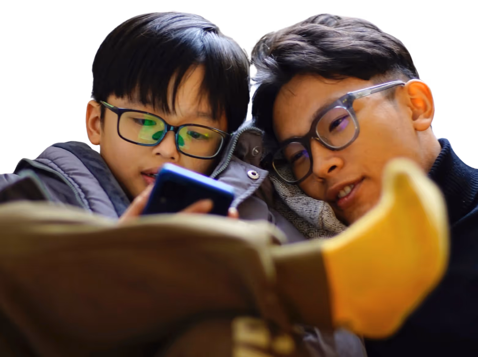 A dad and his young son, both East Asian and wearing glasses, look at a smartphone together companionably.