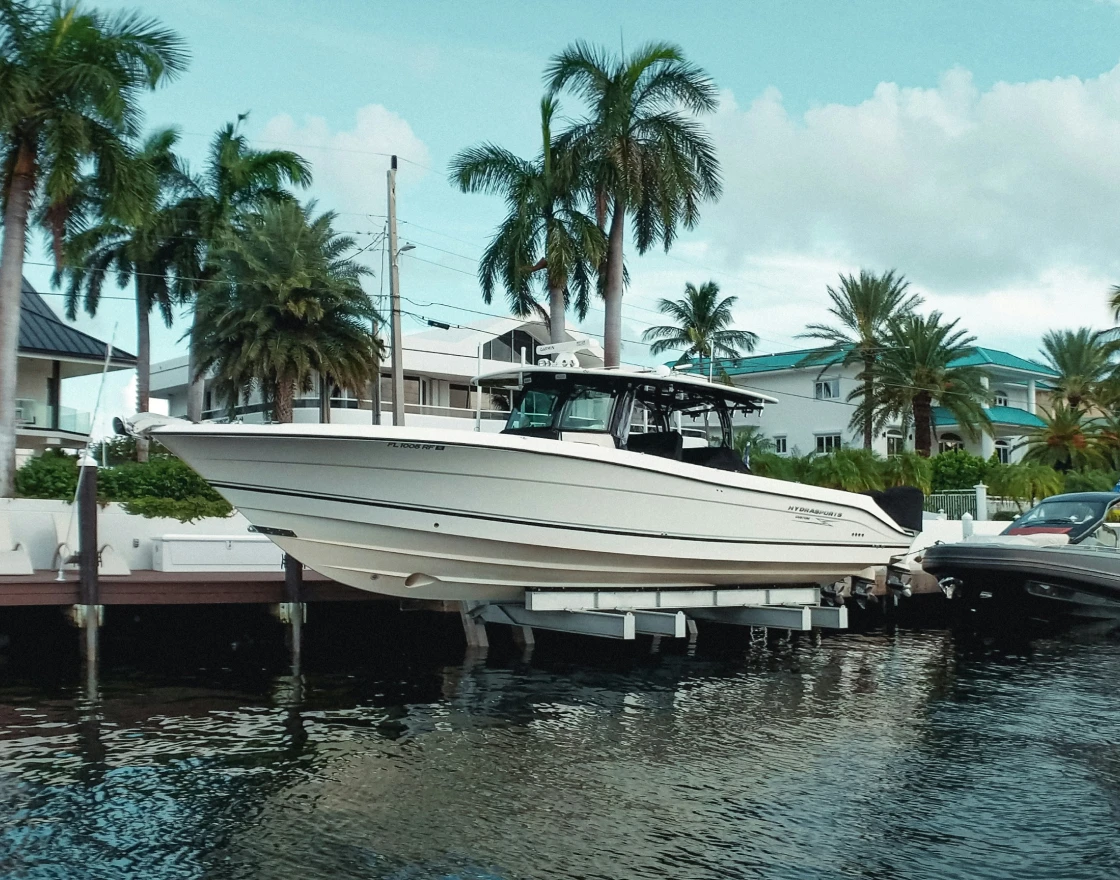 Inside view of a bass boat cockpit showing a steering wheel, control panel with gauges, and black seats with a 'Bass Pro Shops' sign visible outside.