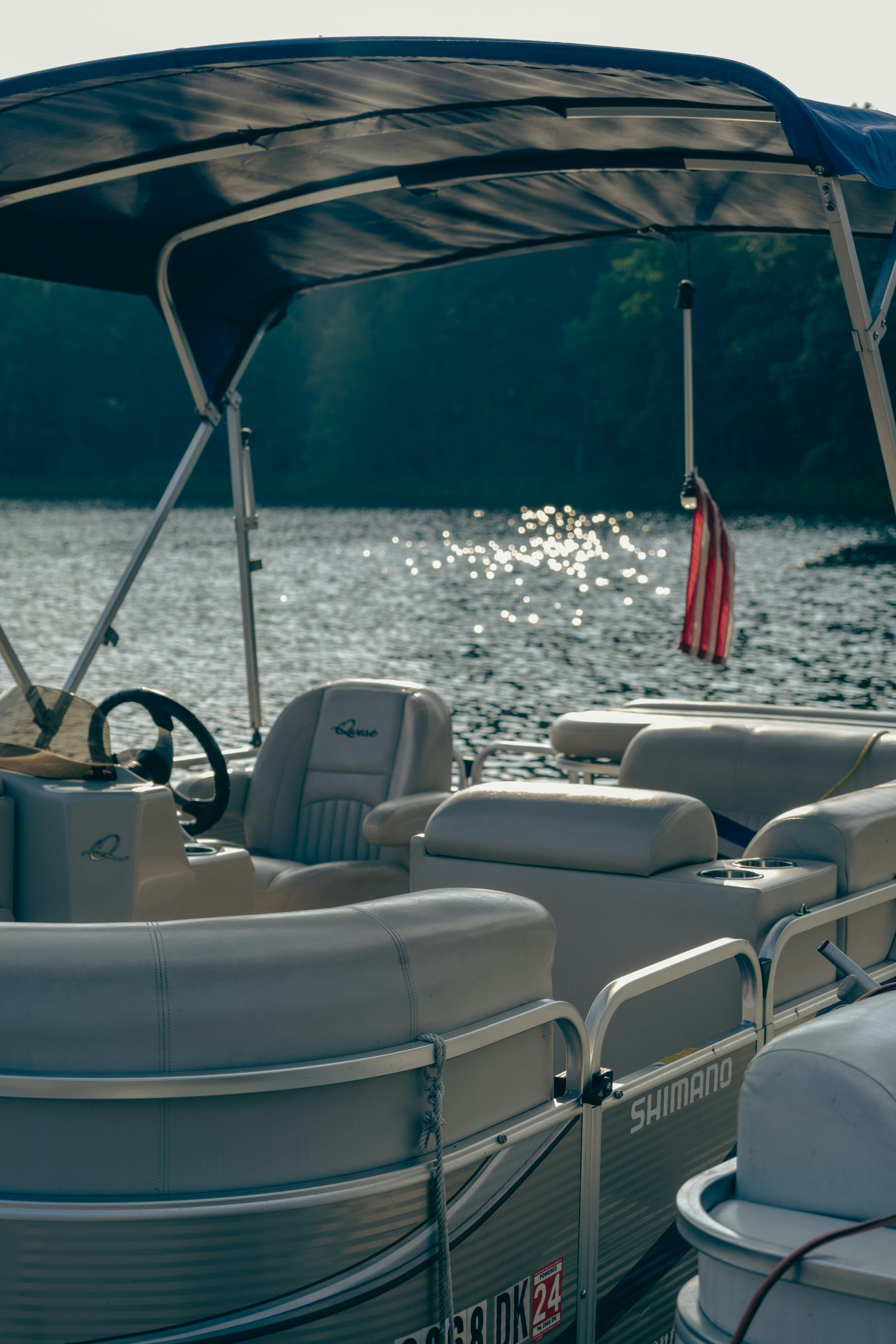 Inside view of a bass boat cockpit showing a steering wheel, control panel with gauges, and black seats with a 'Bass Pro Shops' sign visible outside.
