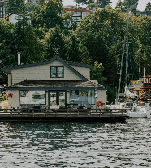 Person fishing from the front of a boat named The Fish Tank on calm open water under a clear sky.