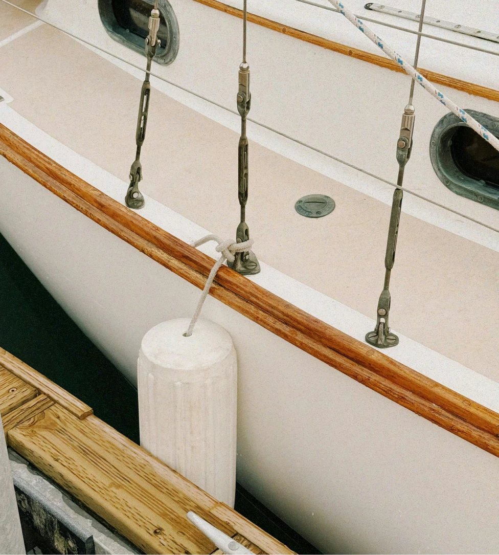 Person fishing from the front of a boat named The Fish Tank on calm open water under a clear sky.