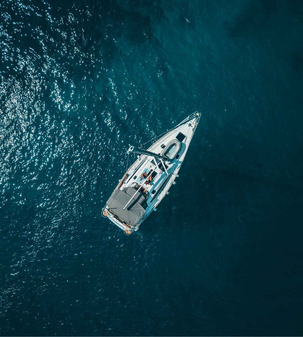 Person fishing from the front of a boat named The Fish Tank on calm open water under a clear sky.