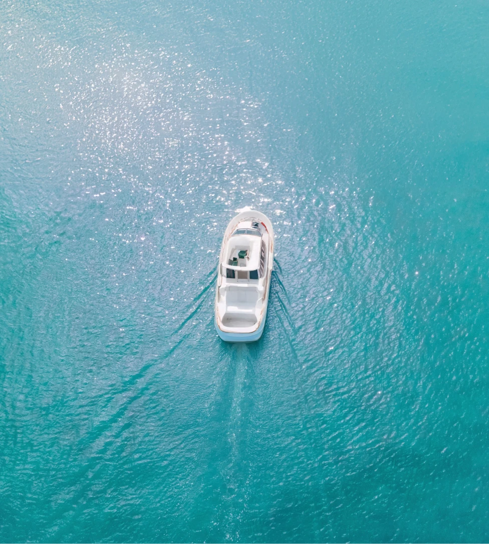 Person fishing from the front of a boat named The Fish Tank on calm open water under a clear sky.