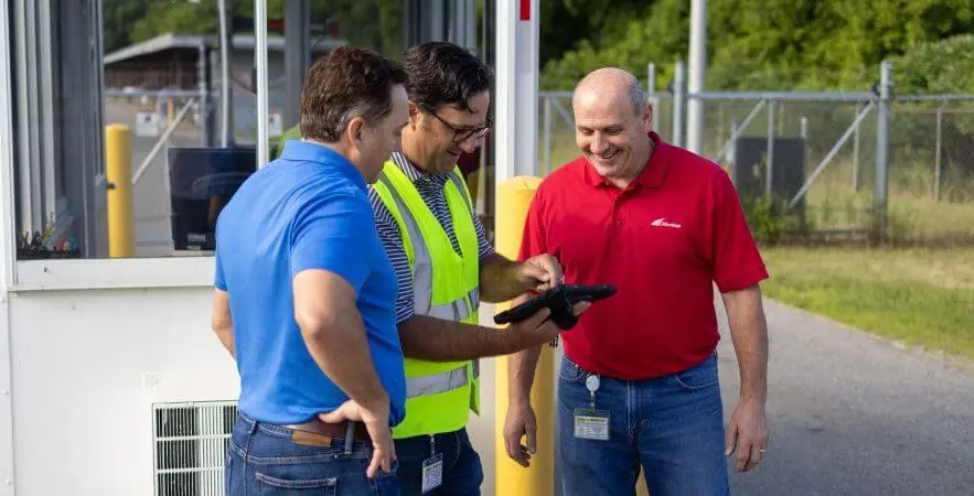 A YardView specialist teaching people how to use YMS software by a gate shack.