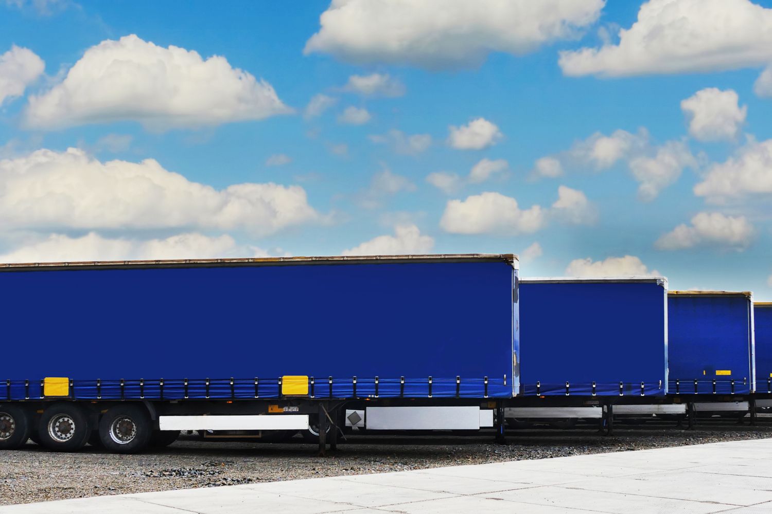 Blue semi-truck trailer containers parked and lined up in a row sitting in an operations yard
