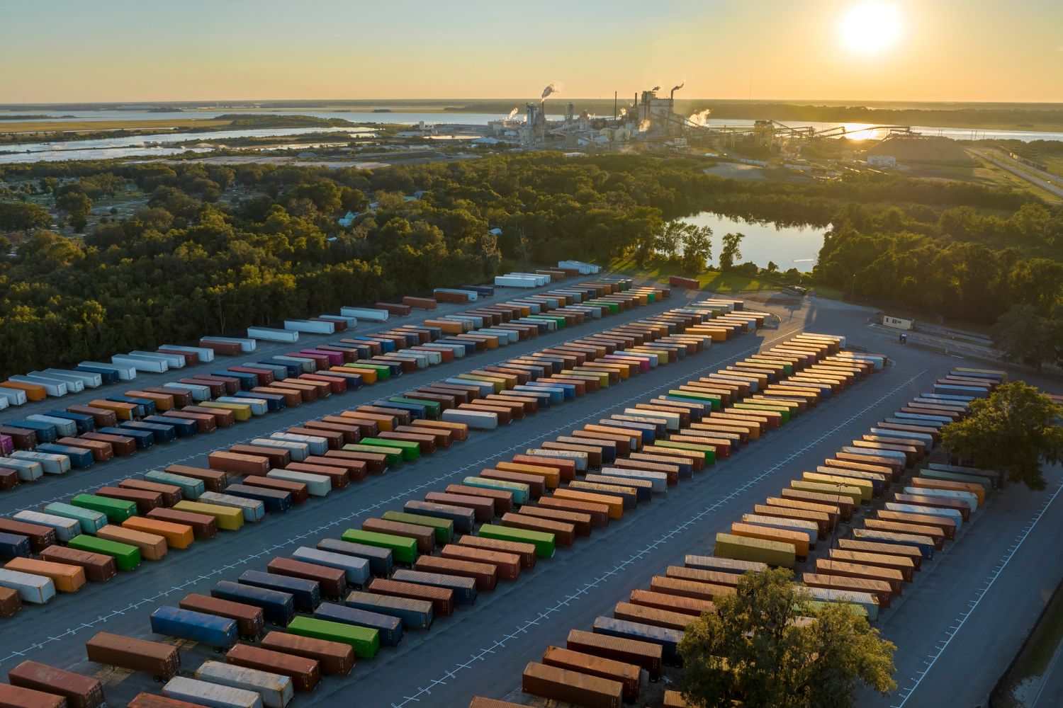 Aerial image of a yard with many cargo/shipping containers at sunset