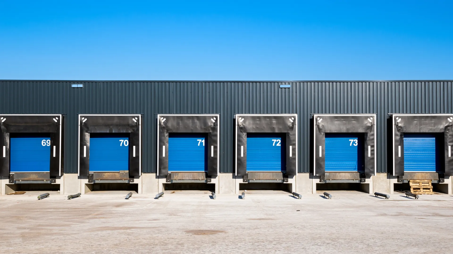 Six blue dock doors with five of them numbered as 69, 70, 71, 72, and 73.