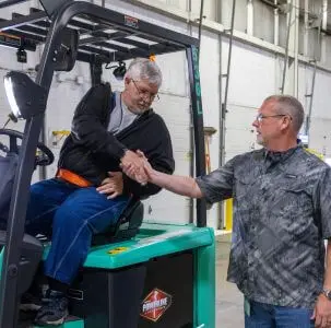 Two warehouse employees shaking hands.