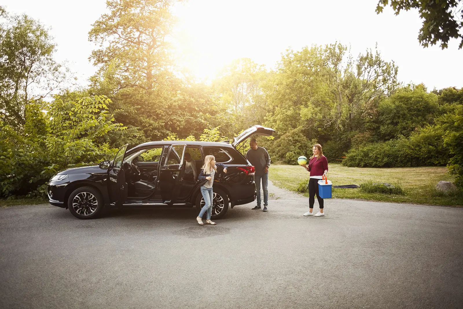 Coche verde estacionado con la familia descargando el vehículo